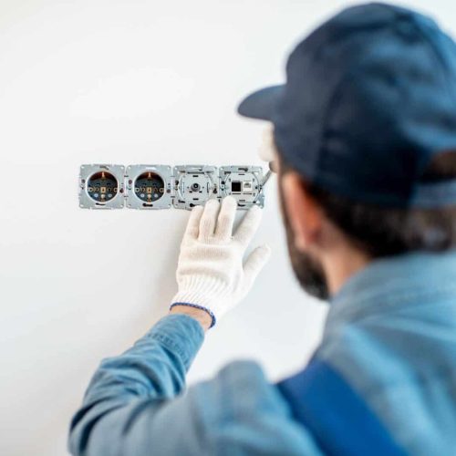 Electrician mounting sockets indoors